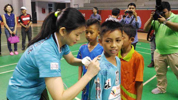 Juara All England 2016 Debby Susanto tengah menandatangani kaos penggemarnya.