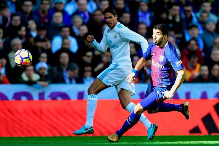 Striker FC Barcelona, Luis Suarez (kanan), berduel dengan bek Real Madrid, Raphael Varane,