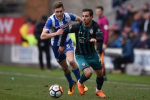Bek Southampton, Cedric Soares, dibayang-bayangi bek Wigan Athletic, Callum Elder, pada pertandingan Piala FA di Stadion DW, Minggu