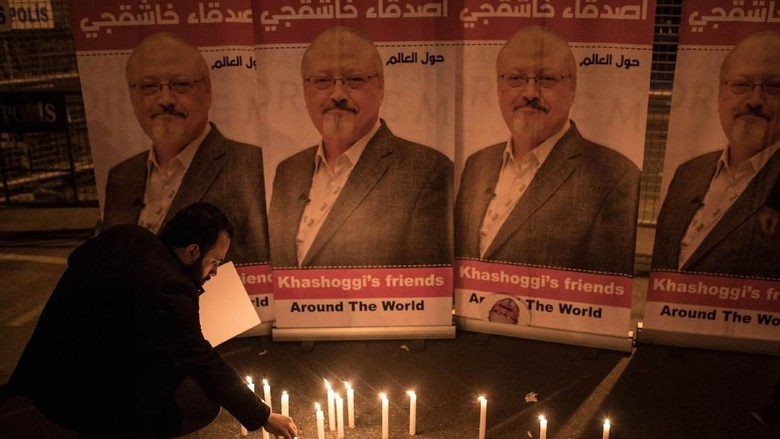 Seorang pria menyalakan lilin di depan poster mendiang Jamal Khassogi