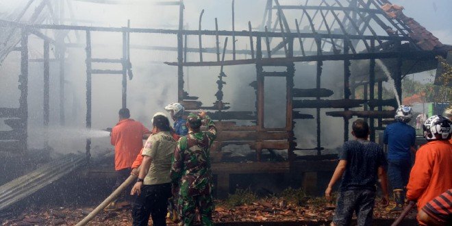 Petugas bersama warga saat memadamkan rumah warga yang terbakar di Desa Lumpatan Muba