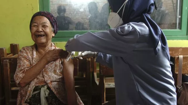 Seorang lansia tertawa lebar saat menerima vaksin